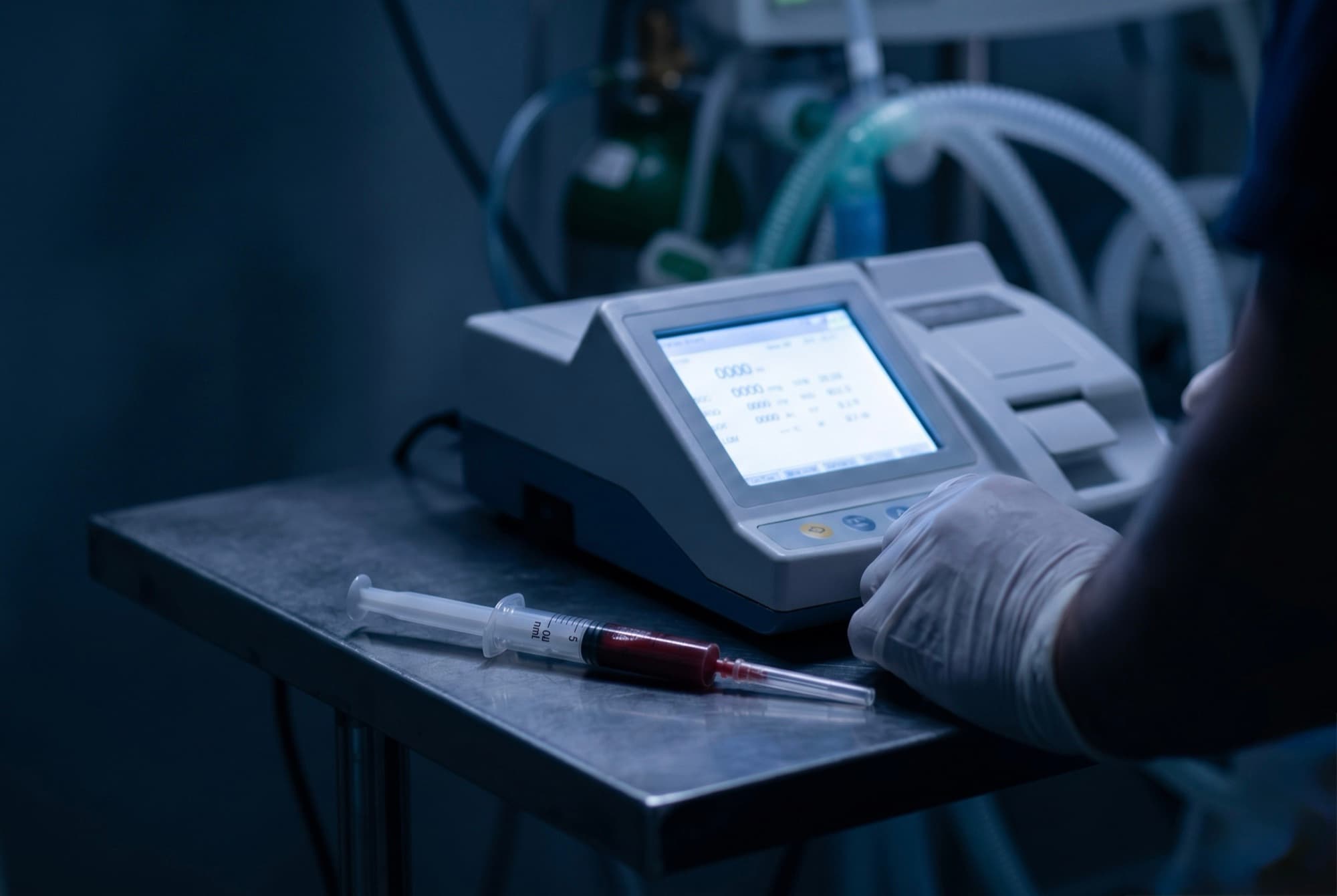 Jeringa con muestra de sangre arterial junto a un analizador de gases