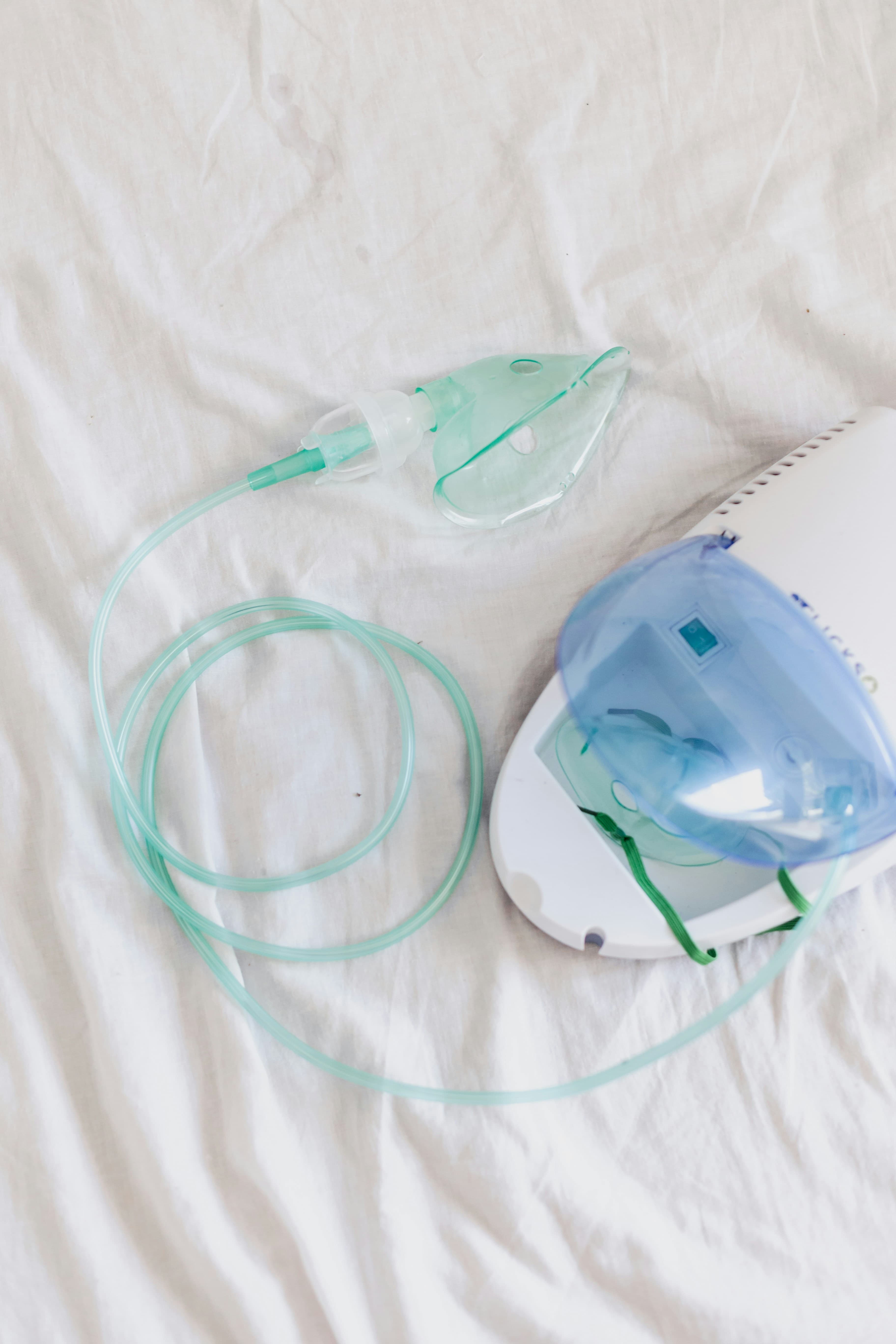 Mascarilla de nebulizador con cámara y tubuladura sobre cama clínica